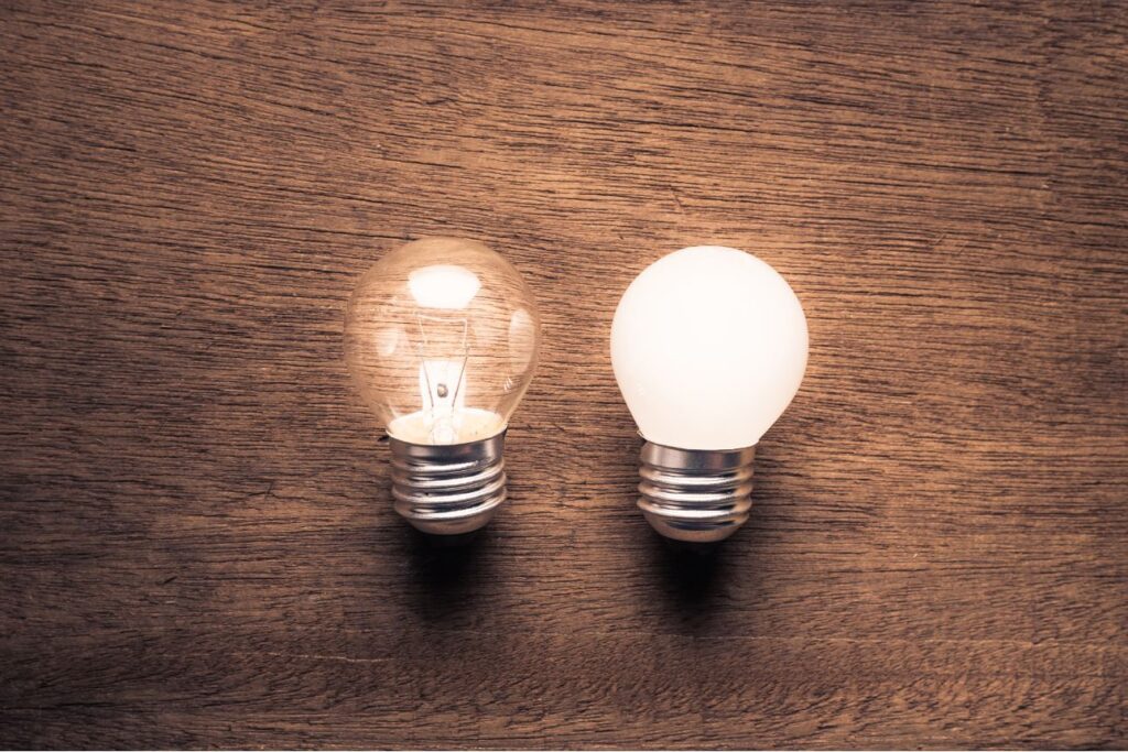 消灯した電球と点灯した電球が並ぶ木目テーブル