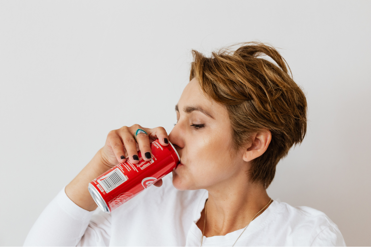 赤い缶飲料を飲むショートヘアの女性