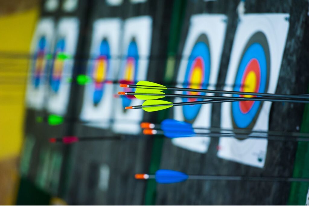アーチェリーの的に命中した複数のカラフルな矢。集中力と精密さを表すスポーツの一場面