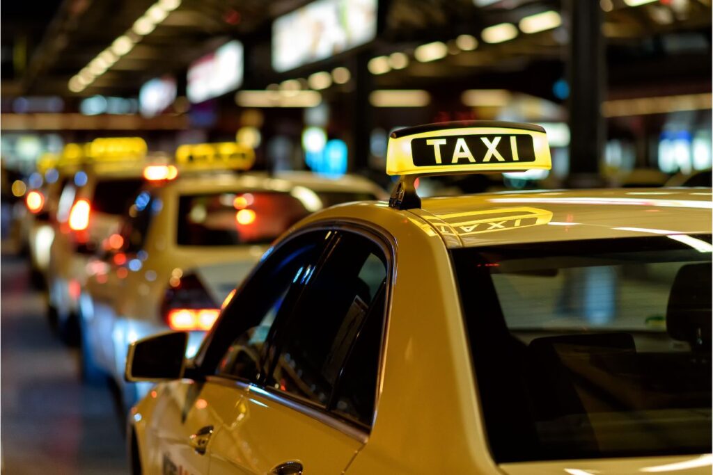 夜の街で並ぶタクシーの列とTAXIサイン。