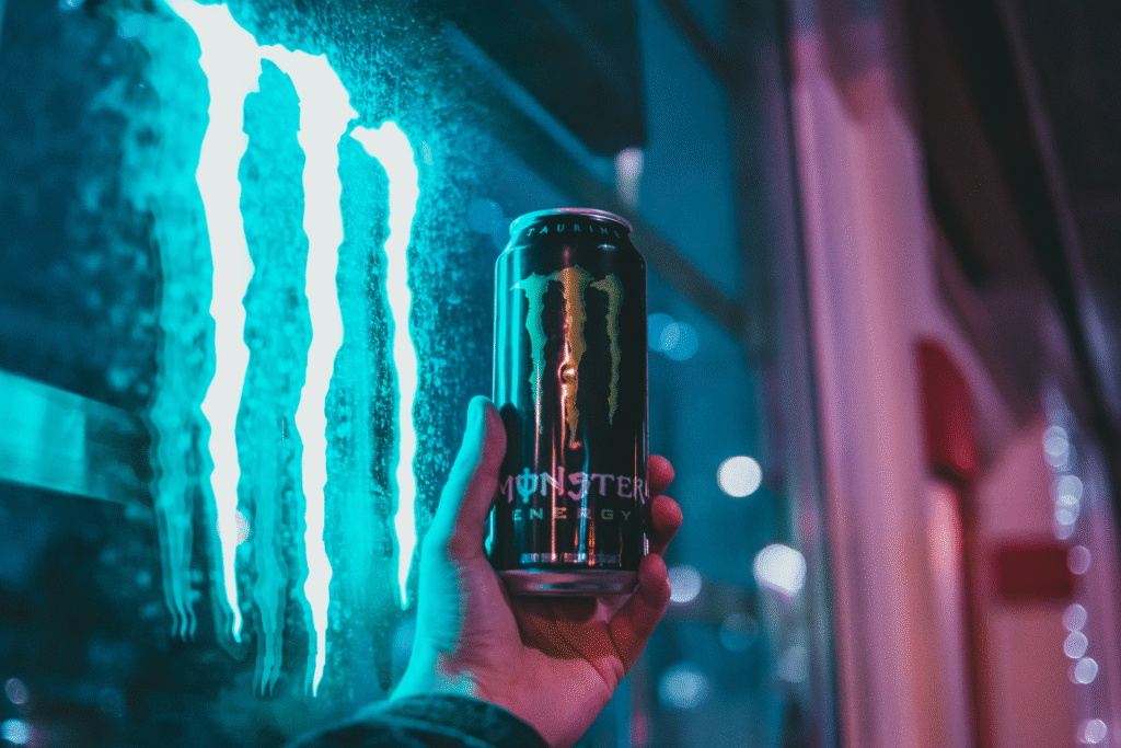 モンスターエナジーの缶を手に持ち、ネオンの反射が印象的な夜の街の背景