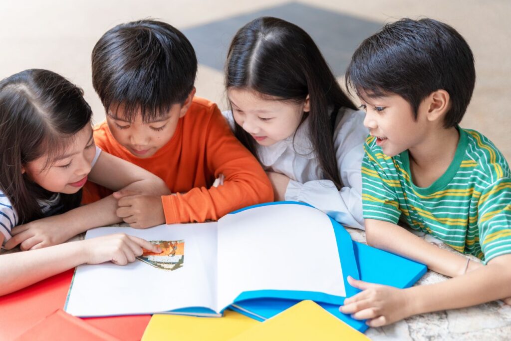 本を囲んで楽しそうに読む4人の子どもたち。