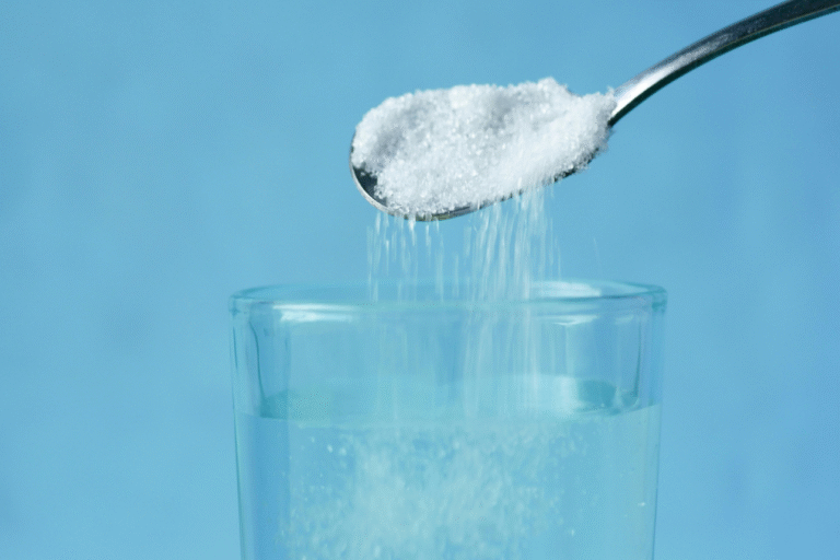 スプーンからグラスの水に砂糖を入れている様子