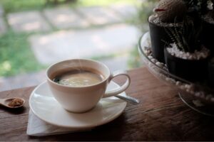 窓辺のテーブルに置かれた湯気の立つコーヒーカップ。穏やかな光の中で、自身の人生について静かに物思いにふけるイメージ