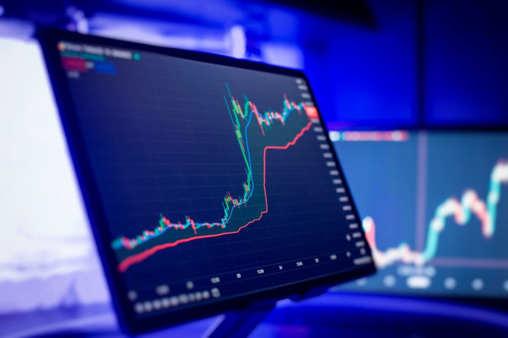 暗いブルーの部屋で光るトレーディング画面に表示された株価チャートとテクニカル指標