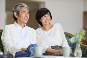 高齢の男女が笑顔でソファに座る写真。