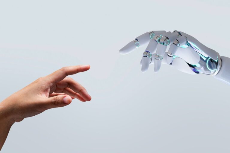 人間の手とロボットの手が触れ合おうとする未来的なイメージ。