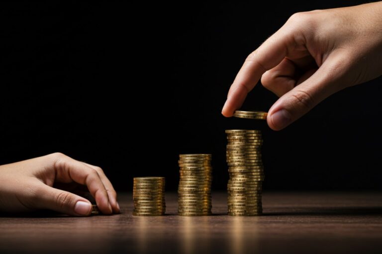 積み上がる金貨の山と手、格差や資産の象徴。