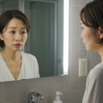 鏡に映る自分の顔を見て、老化の兆候にため息をつく中年女性。