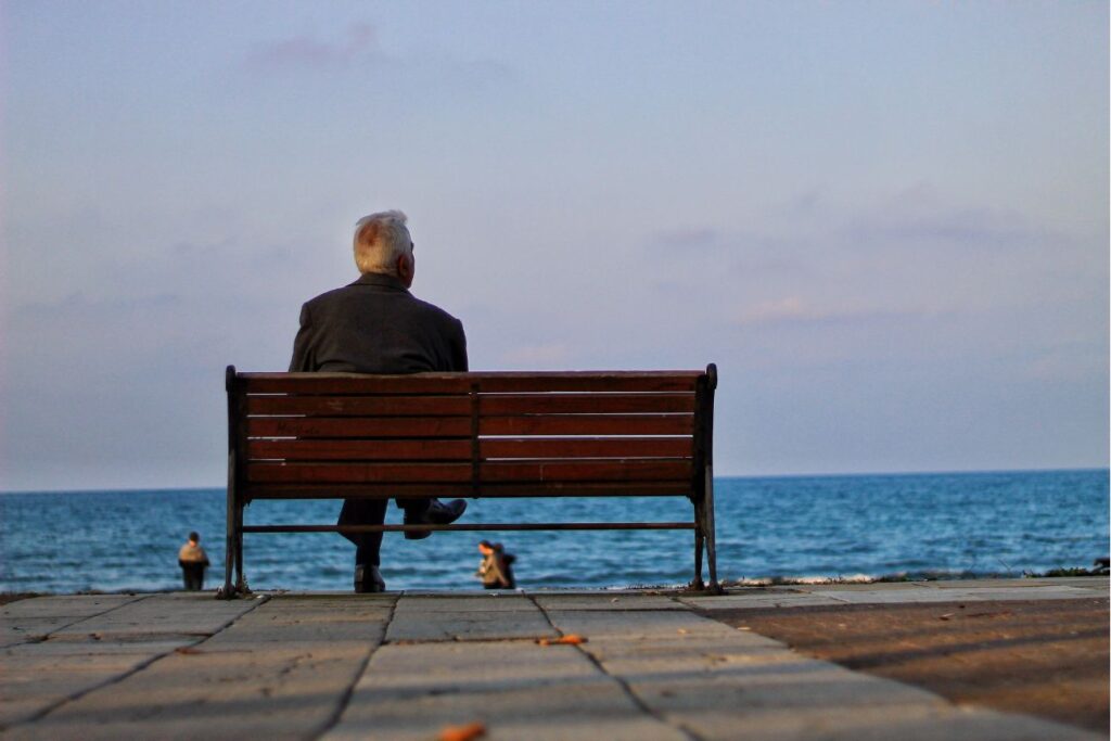 海を見つめる高齢男性の後ろ姿。孤独や老後の時間、心の健康を象徴する風景