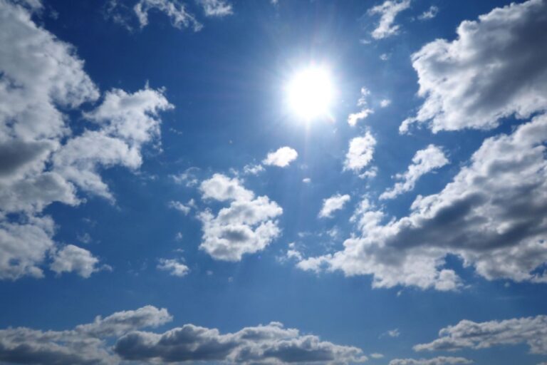 快晴の青空にまぶしく輝く太陽と、点在する白い雲