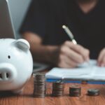 貯金箱と硬貨を並べて家計簿をつける人