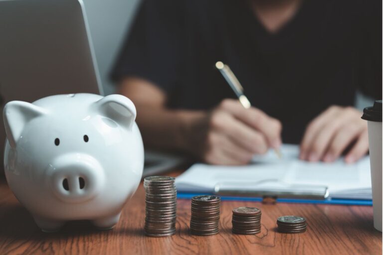 貯金箱と硬貨を並べて家計簿をつける人