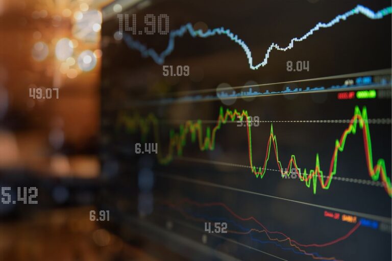 複数の株価チャートや数値が表示されたトレーディングスクリーンのクローズアップ画像。価格変動を示す緑・赤・青のラインが並ぶ