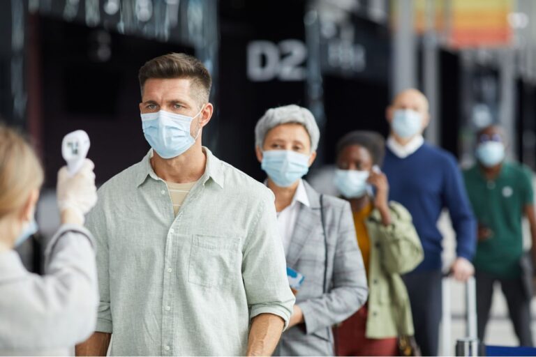 空港でマスクを着用し、非接触型体温計で検温を受ける人々。新型コロナウイルス対策の一環