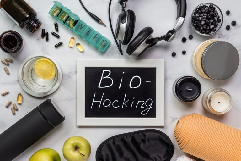 サプリやピルケース、ヘッドホンなどバイオハッキング用品を並べたフラットレイと「Bio-Hacking」の黒板